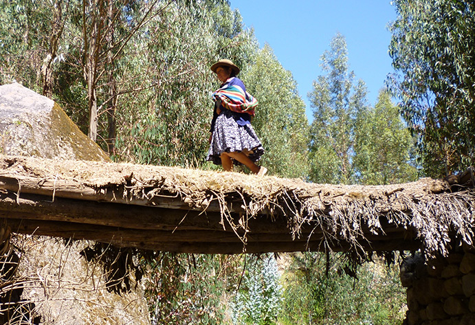 Una mujer cruza un puente del Qhapaq Ñan