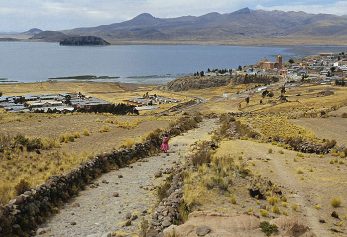 Una mujer camina por el Camino a orillas del lago Titicaca