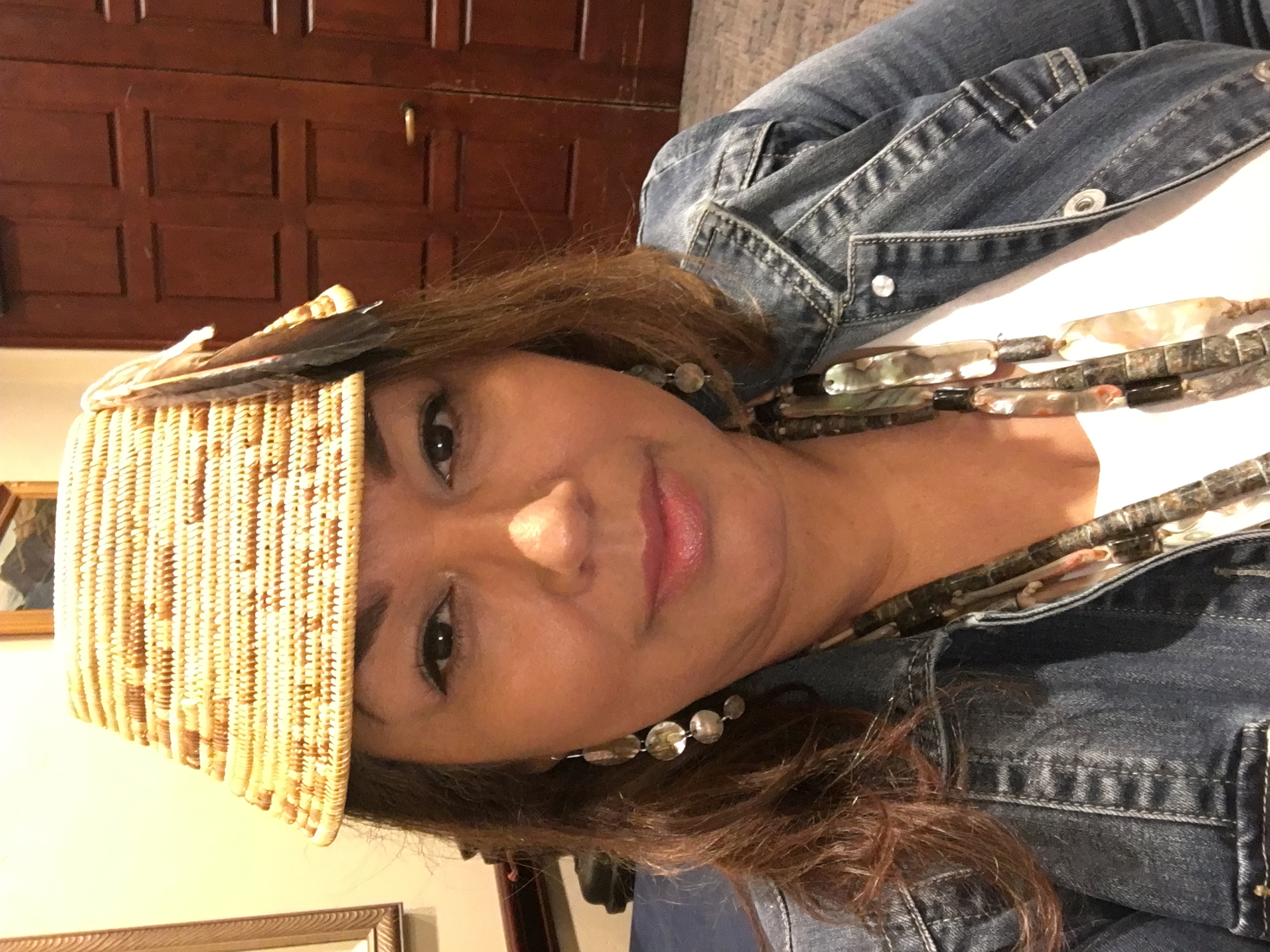 Headshot of a woman wearing a woven hat and a denim jacket
