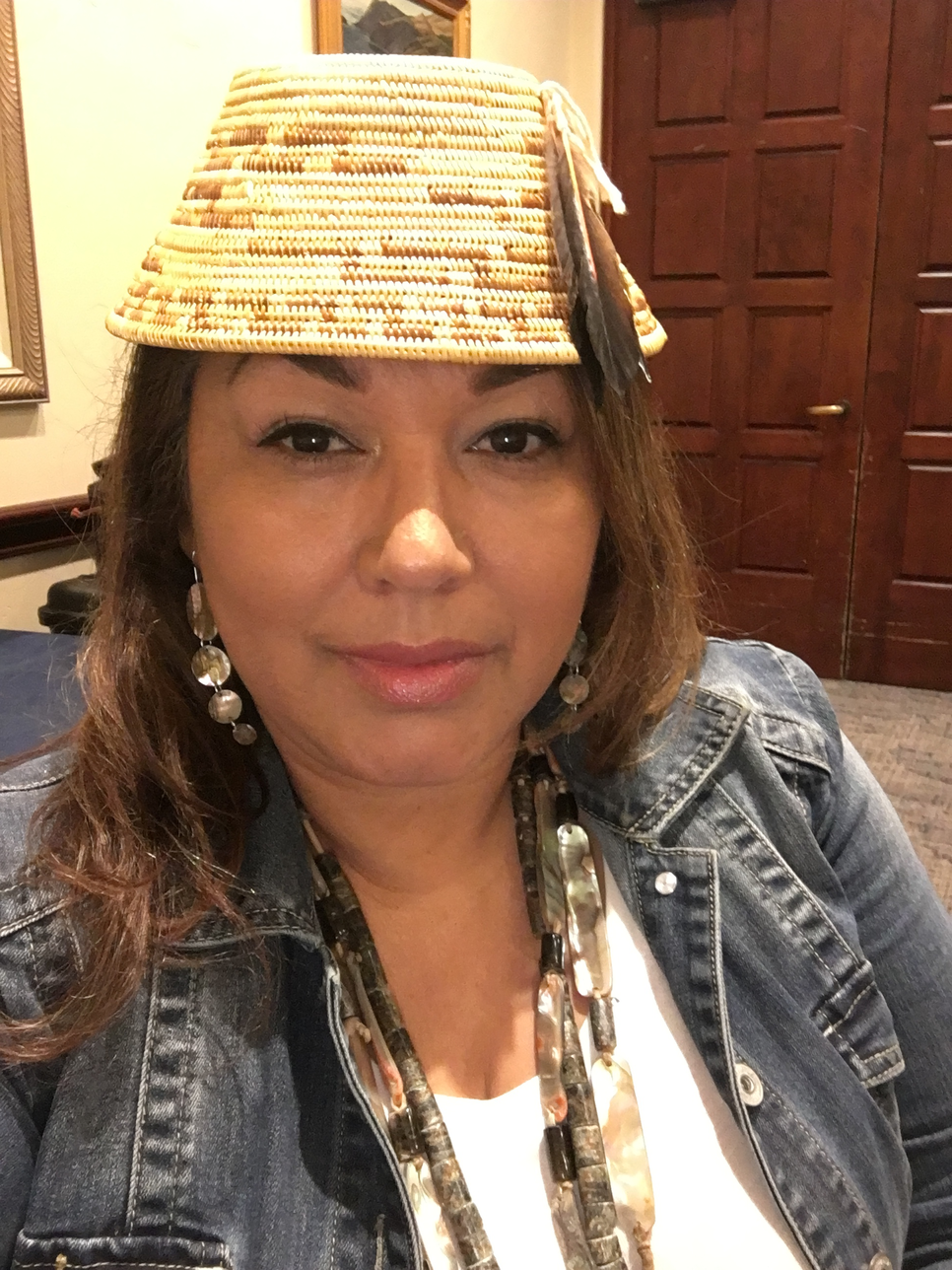 Headshot of a woman wearing a woven hat and a denim jacket