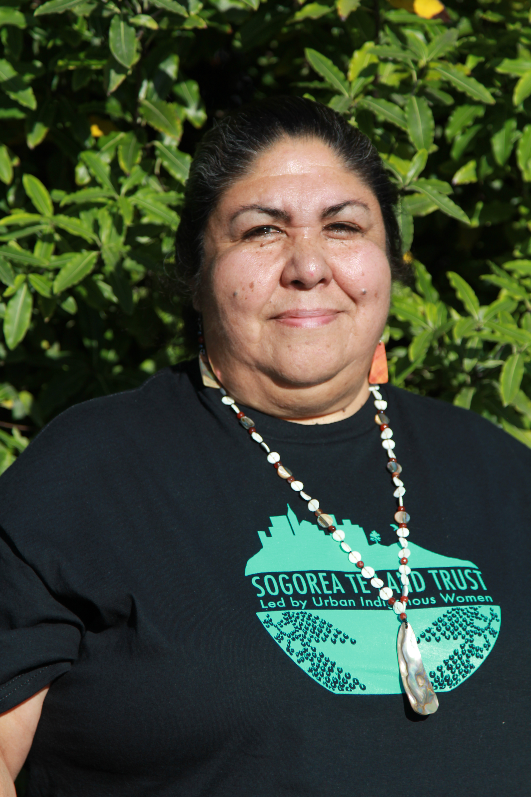 Headshot of a woman wearing a dark t-shirt and a beaded necklace