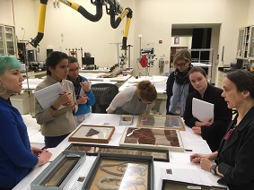 People standing around a table that has objects dispayed upon it