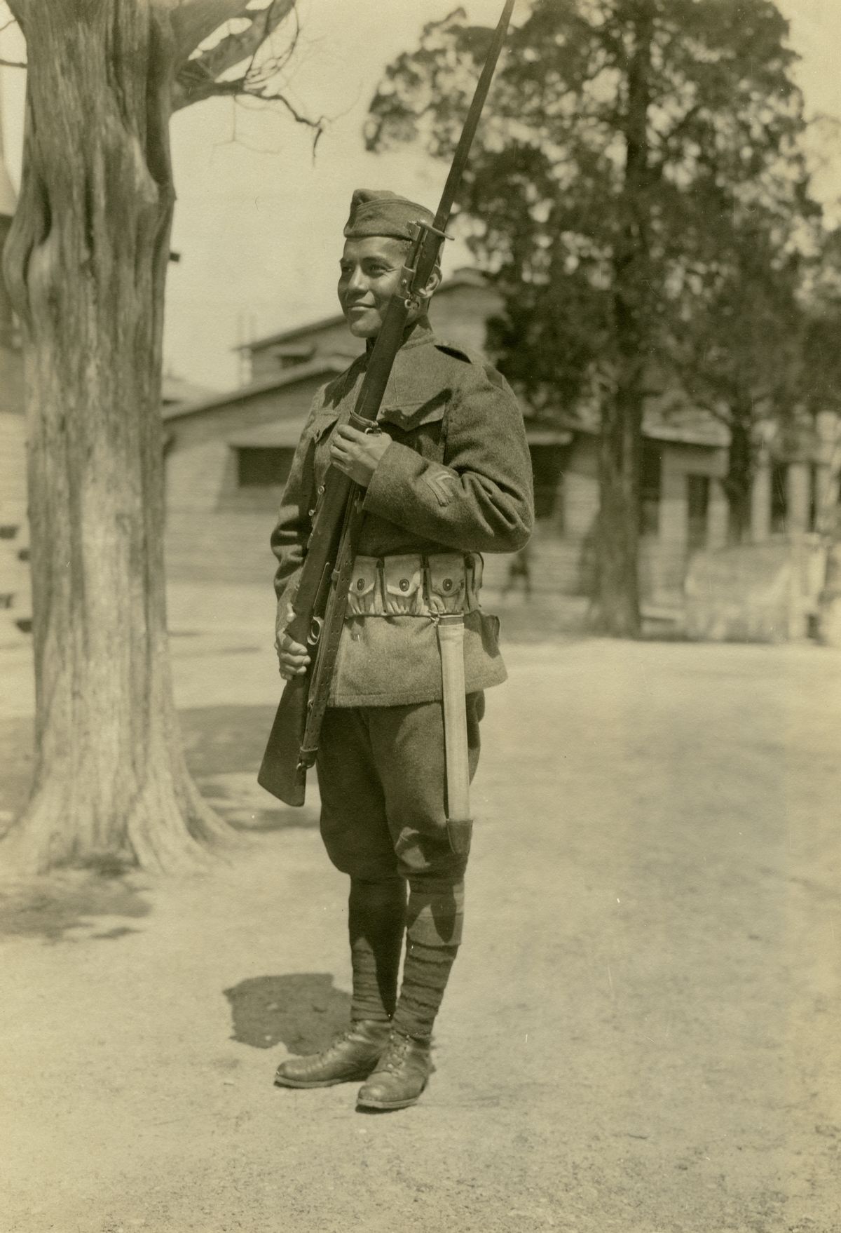 Soldier Amado Garcia standing at an angle in uniform and holding a rifle at Camp Dix, New Jersey