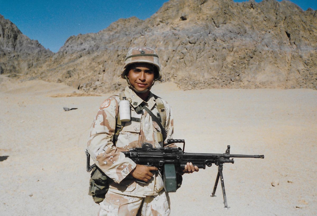 Soldier Manuel Hernandez in uniform holding a rifle in the desert location of Karshi-Khanabad, Uzbekistan